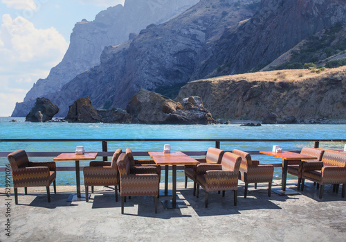 Street cafe on the pier by the sea against the backdrop of mountains