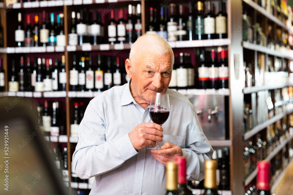Elderly man smells the quality of red wine. High quality photo