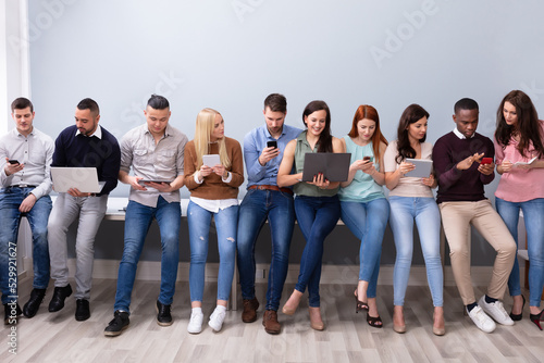 Group Of Young People Using Various Electronic Gadgets