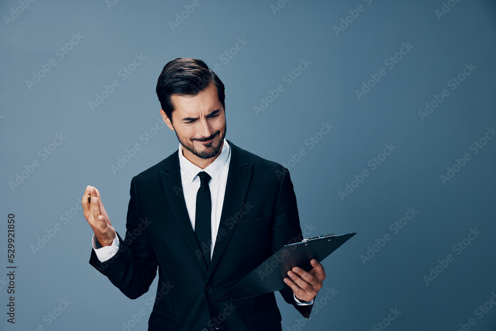 Portrait of a business man in a stylish suit smile with tie beautiful face on a blue isolated background with a tablet in his hands. Business concept young businessman startup copy place