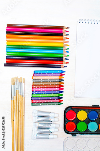 Watercolor oil paints, paintbrushes, colorful pencils, pastel crayons,blank watercolor paper pad. Creativity creation process. Artist's stuff on white table.Top view Flatlay of drawing supplies