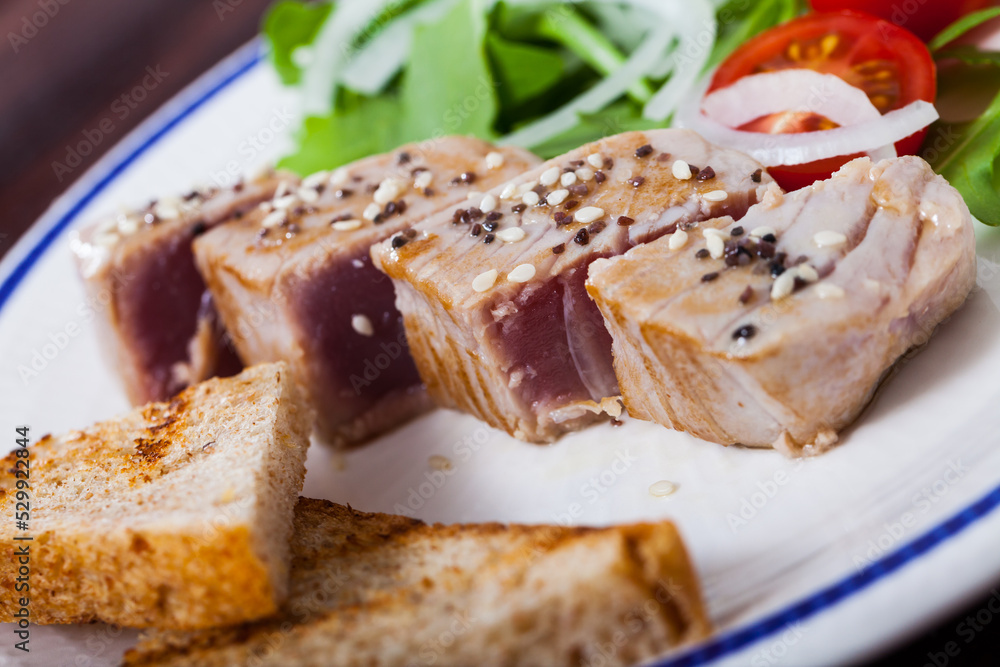 Tataki (tuna fillet) served with toasts and greens on plate