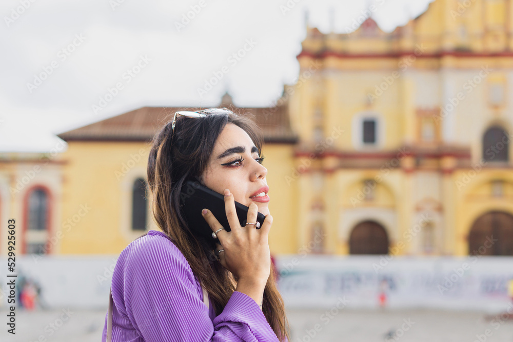 Woman smiling and talking on the phone in the street. Woman smiling and talking on the phone in the street.