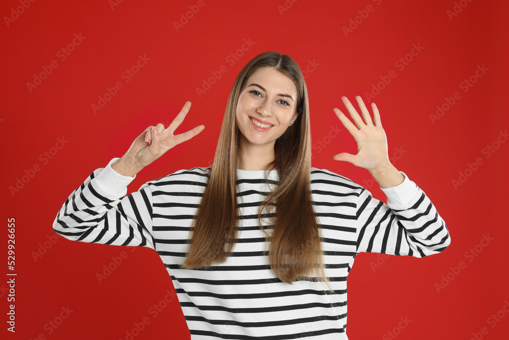 Woman showing number seven with her hands on red background Woman showing number seven with her hands on red background