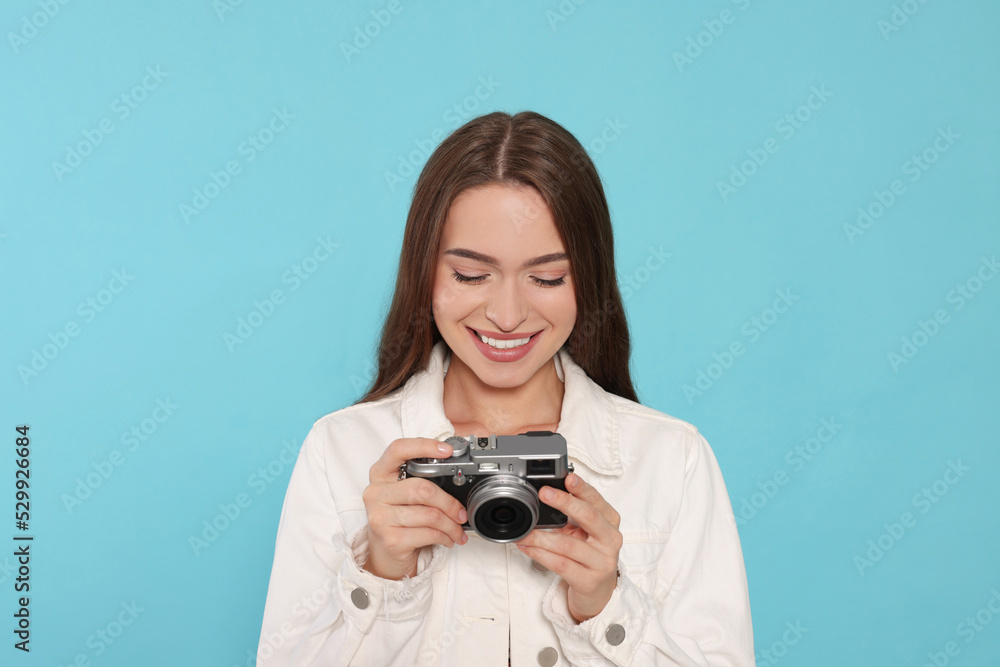 Young woman with camera on light blue background. Interesting hobby Young woman with camera on light blue background. Interesting hobby