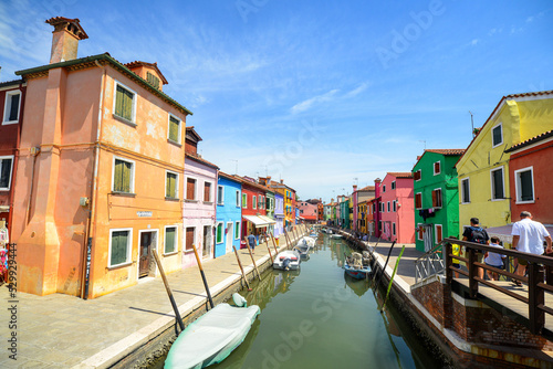 Tourists among the sovereign shops on the main street of burano Island,  Colorful houses on the canal. Venice, Italy. © opasstudio
