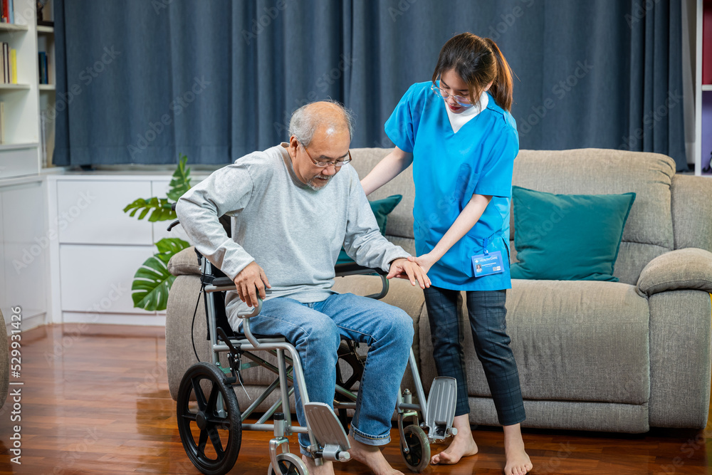 Asian nurse assisting helping senior man patient get up from wheelchair for  practice walking at home, Smiling doctor support old man to getting up,  help handicapped elderly stand up, healthcare Photos