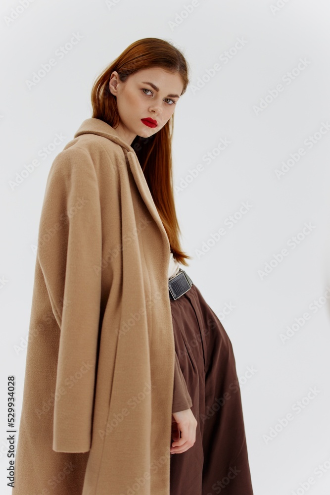A red-haired lady in a beige coat on a white background. Advertising for brands showrooms catalog of clothing for women A red-haired lady in a beige coat on a white background. Advertising for brands showrooms catalog of clothing for women