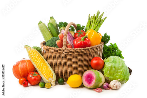 wicker basket fill up with different fresh vegetables on white background.
