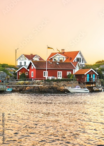 Vertical shot of a small houses of Kyrkesund on the lakeside and a boat in water at sunset in Sweden photo