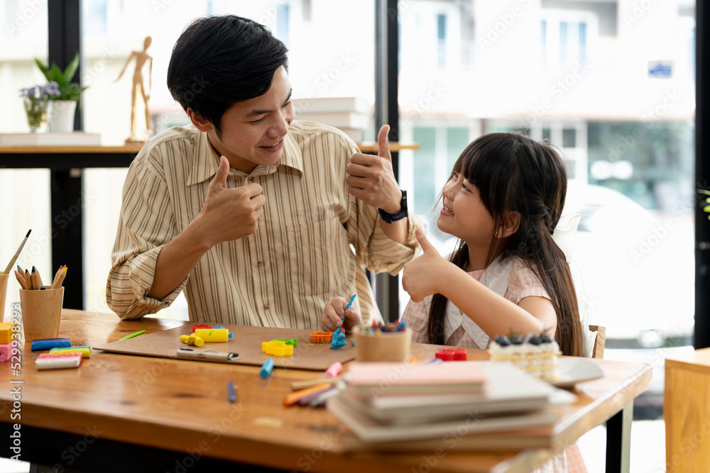 Proud asian father and daughter plasticine or play dough on a table dough together