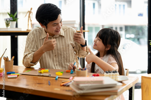 Proud asian father and daughter plasticine or play dough on a table dough together