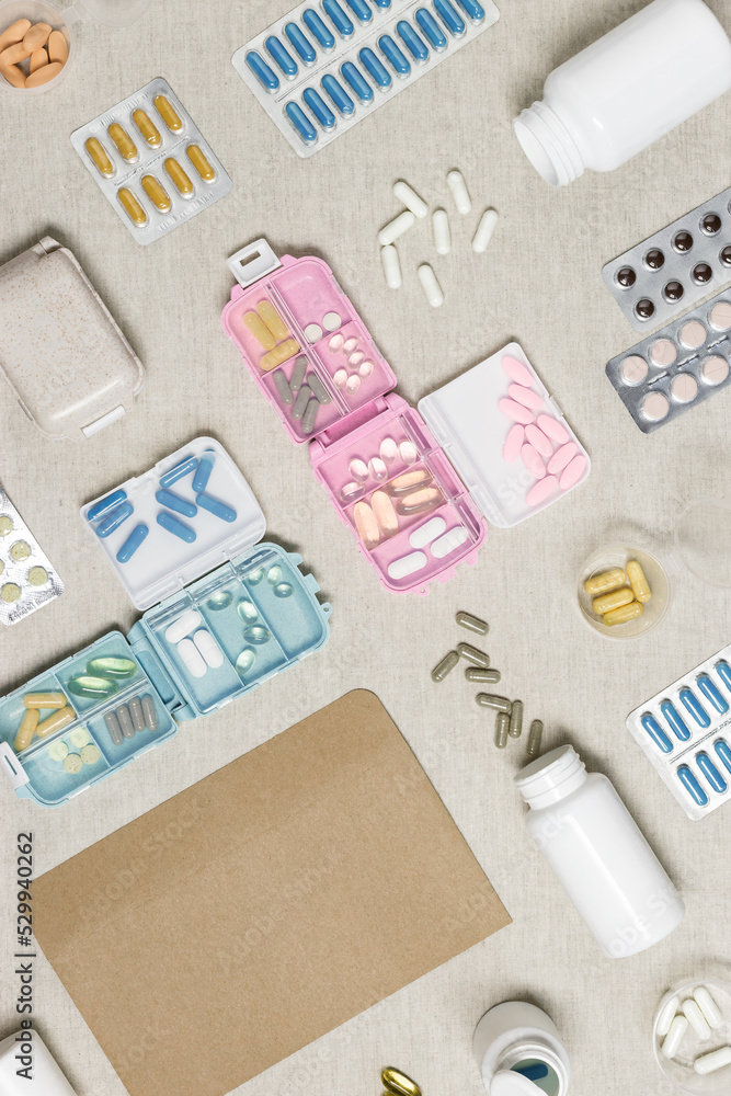 Pills box for daily intake of vitamins and medicines on cloth background. Top view various capsules and tablets, medical background. Lifestyle for beauty and health, flat lay, empty space Pills box for daily intake of vitamins and medicines on cloth background. Top view various capsules and tablets, medical background. Lifestyle for beauty and health, flat lay, empty space