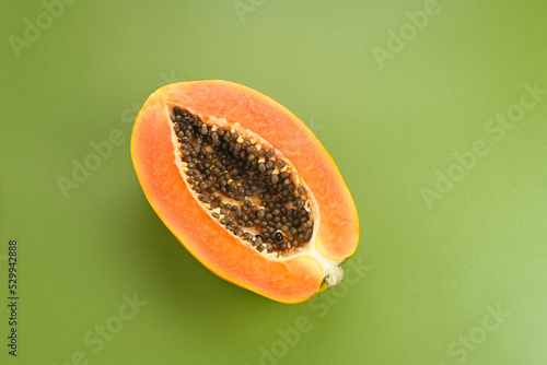 Papaya cut in half on green background, space for text
 photo