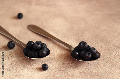fresh blueberries in a metal spoon on a gray background