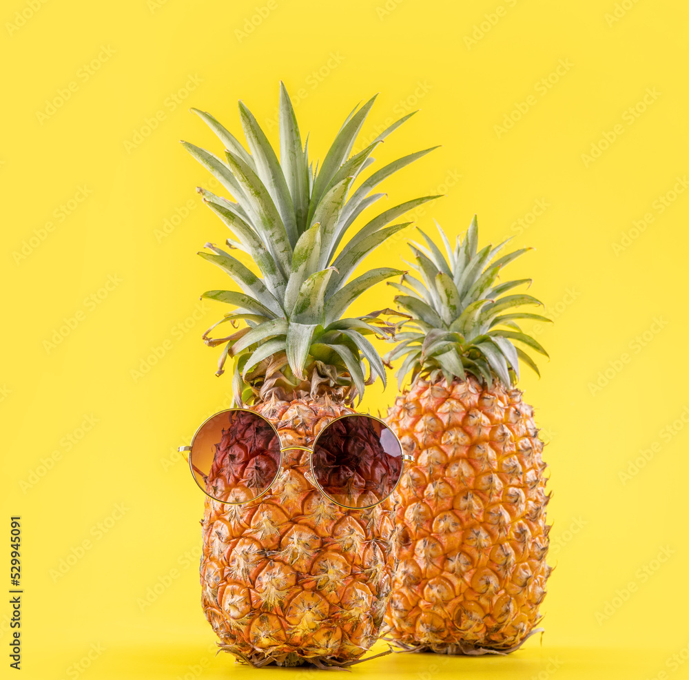 Obraz Creative pineapples with sunglasses isolated on yellow background, summer vacation beach idea design pattern, copy space, close up, blank for text fototapeta, plakat