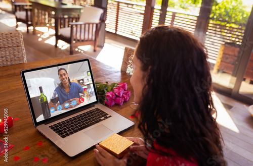 Happy multiracial young couple dating on video call through laptop during valentine day