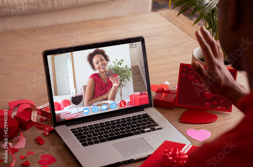 Happy biracial young couple dating on video call through laptop during valentine day