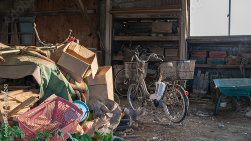 農家の納屋に積まれた荷物と自転車と野菜の苗（縦）