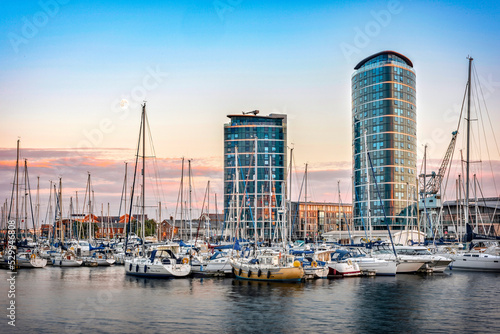 Chatham maritime marina at sunset. Reflection on water, yachts, two modern skyscrapers on background, moon and copy space in clear sky. photo