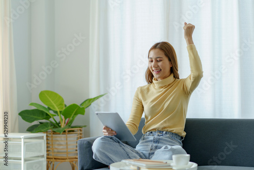Vászonkép Young Asian business women are delighted and happy with their work and success on their tablet at home