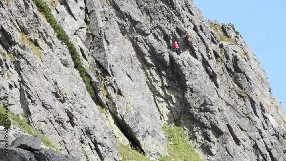 Lonely Mountain Climber Slowly Climbs Steep Wall With Helmet and Ropes, Boulder Telephoto Lonely Mountain Climber Slowly Climbs Steep Wall With Helmet and Ropes, Boulder Telephoto