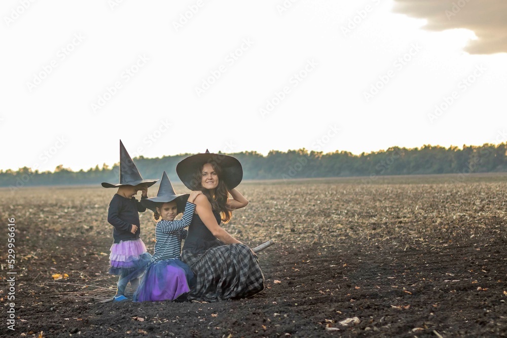 Happy Halloween. cheerful family of witches flies on a broomstick. Mother and children in