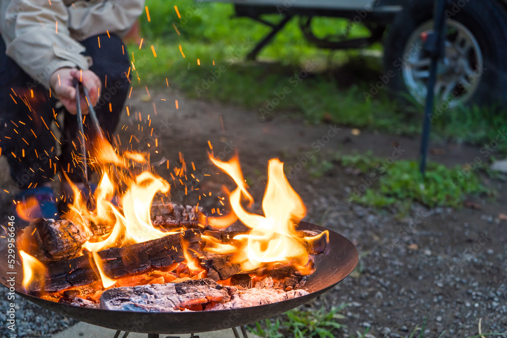 キャンプ場で焚き火を楽しむ人