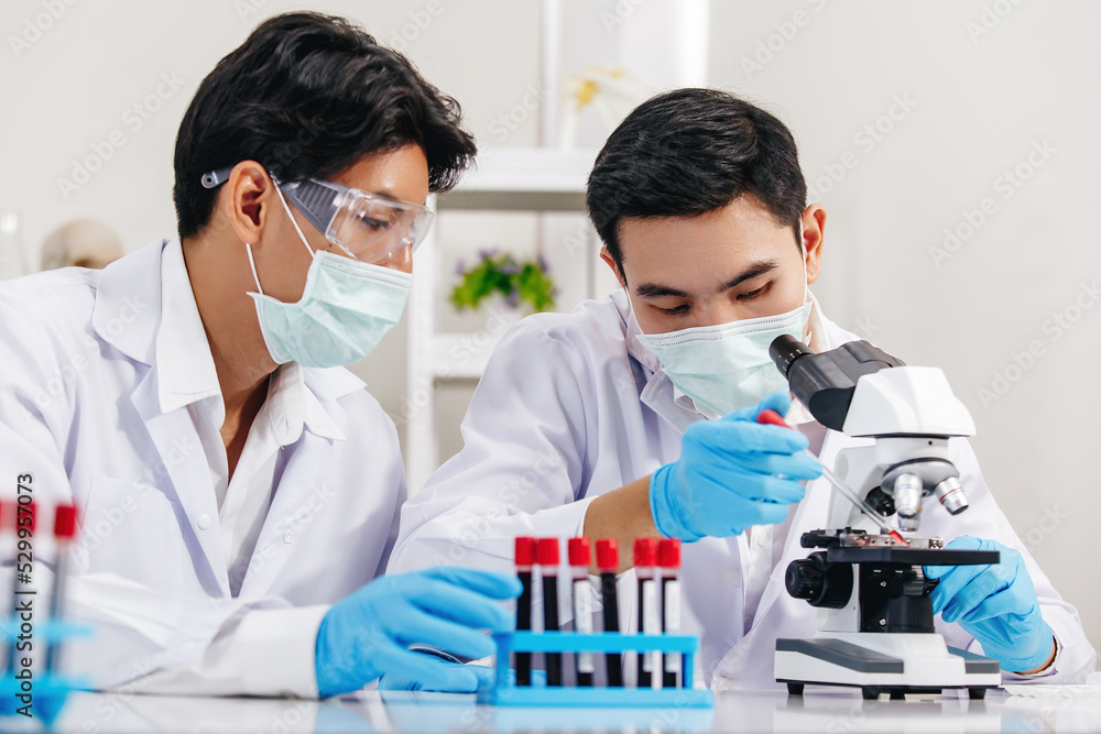 Two Male Scientists with Mask working in Lab while Checking Result of Blood Sample testing.
