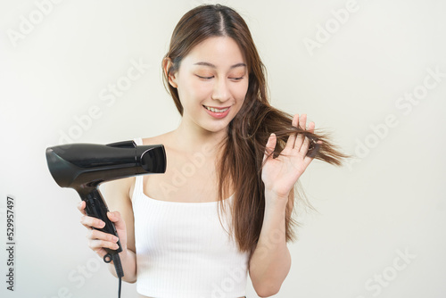 Hair Dryer, beautiful happy, asian young woman, girl hand in using, holding hairdryer to dry, blowing blonde long straight after shower at home. Hairdressing, hair treatment isolated on background.