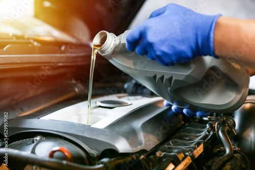 Car oil is pouring into the engine close up. pouring new oil into the engine. automobile engine oil change. vehicle maintenance concept