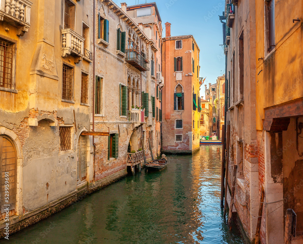 View on the narrow cozy streets of the canals with parked boats in Venice, Italy. Architecture and landmark of Venice.