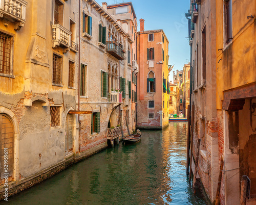 View on the narrow cozy streets of the canals with parked boats in Venice, Italy. Architecture and landmark of Venice.