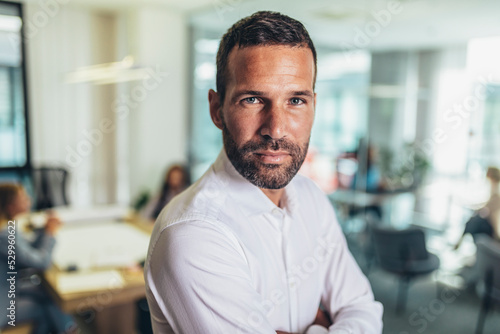 Portrait of a handsome young businessman in modern office smiling looking at the camera
