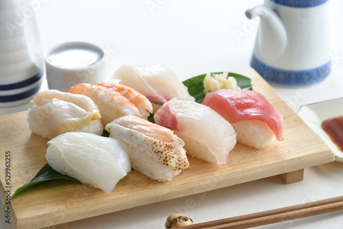 Sushi Set nigiri sashimi and on wooden serving board with soy sauce and Japanese Sake over white background-Jananese Food