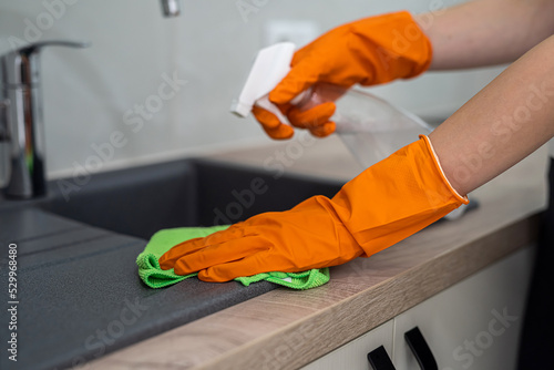 closeup view, female hand wearing rubber protective gloves and clean kitchen