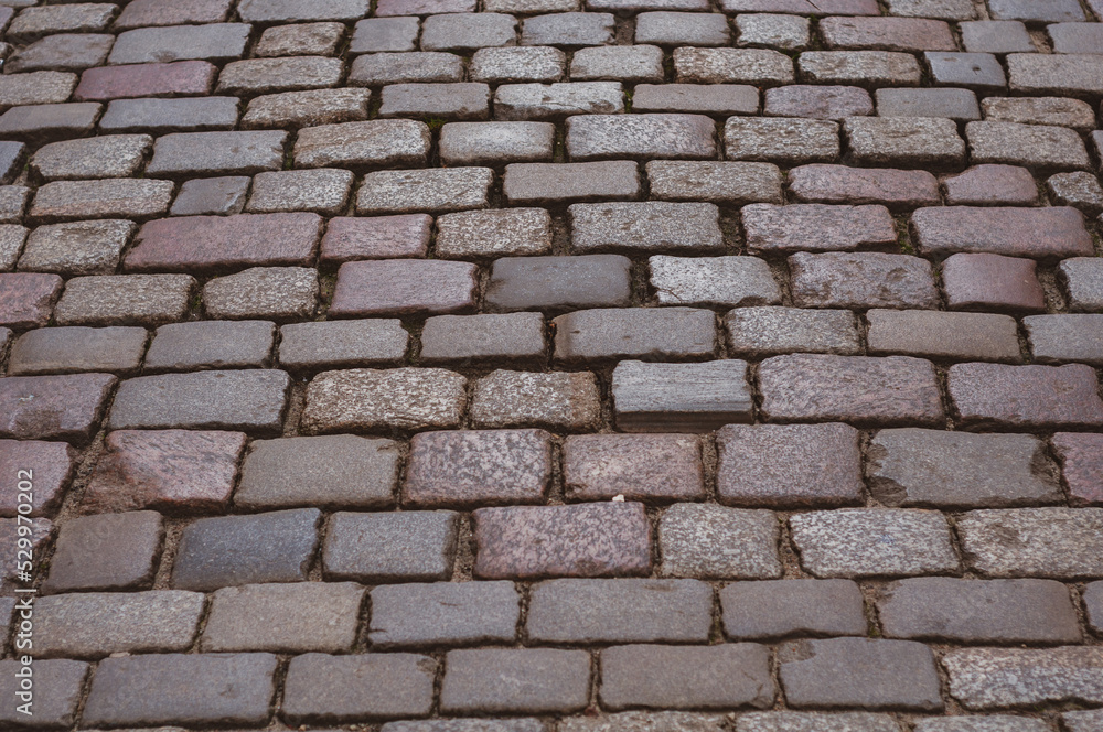 Old pavement lined with stone, stone pavement background close-up.