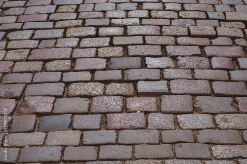 Old pavement lined with stone, stone pavement background close-up.