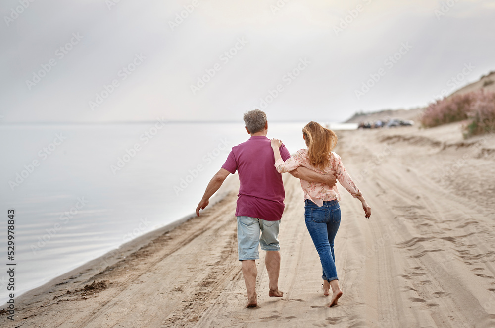 Father and daughter walking together on sand at sunset Father and daughter walking together on sand at sunset