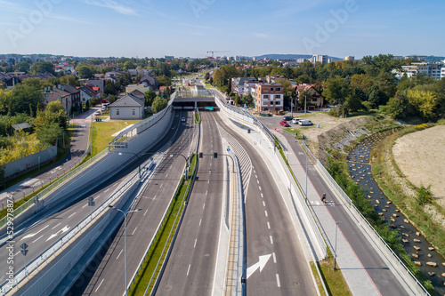 New city highway Trasa Lagiewnicka in Krakow, Poland, with tunnels, slip ways, cycle path and pavement for pedestrians. Regulated Wilga river decorated with stones