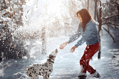 Playful woman with Dalmatian dog in snow at park
