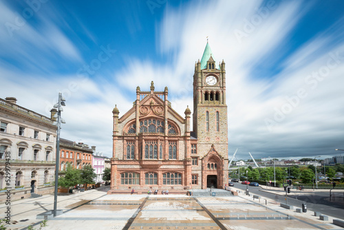 Guildhall with clock tower in city under cloudy sky