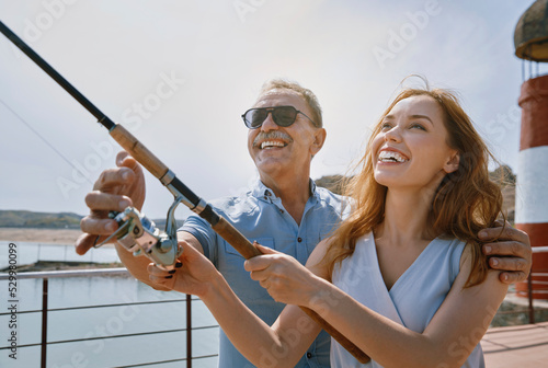 Father teaching his daughter to do fishing at jetty