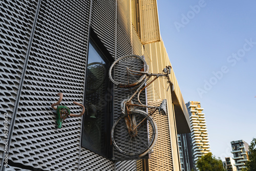 Old bicycle mounted near window of modern building photo