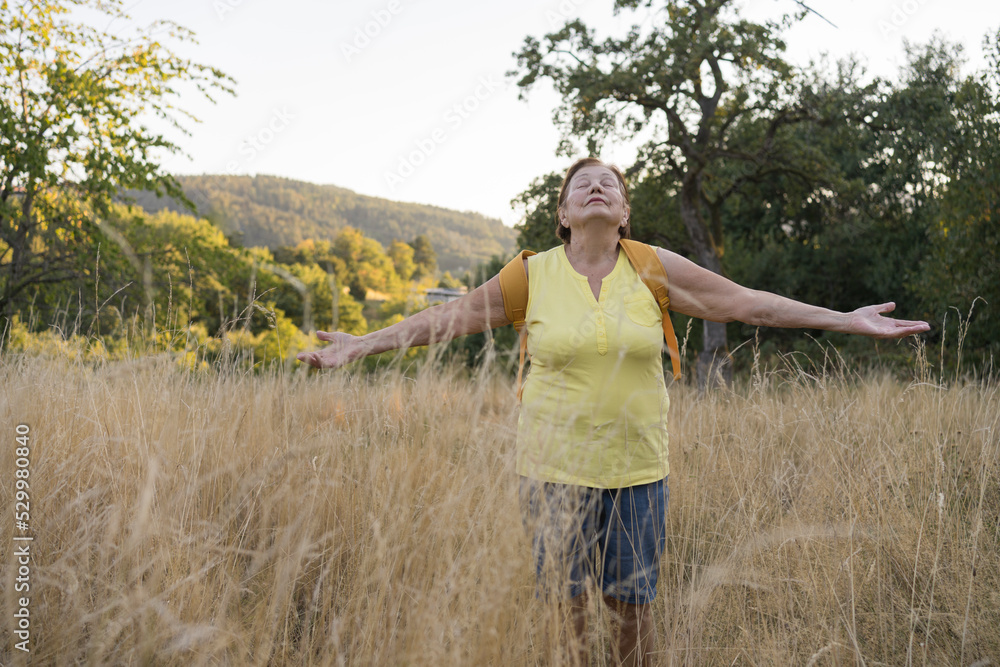 Senior woman with arms outstretched standing in field Senior woman with arms outstretched standing in field