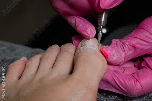 The master makes hardware pedicures to the client. Cuticle treatment. 