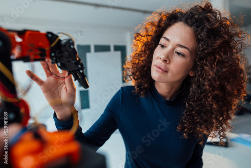 Engineer examining robotic arm in office