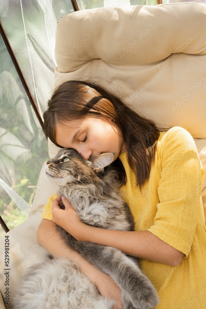 Girl with eyes closed embracing cat on hanging chair Girl with eyes closed embracing cat on hanging chair