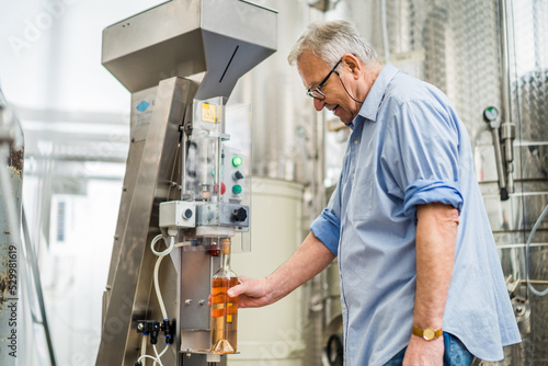 Man filling wine from storage tank in winery.