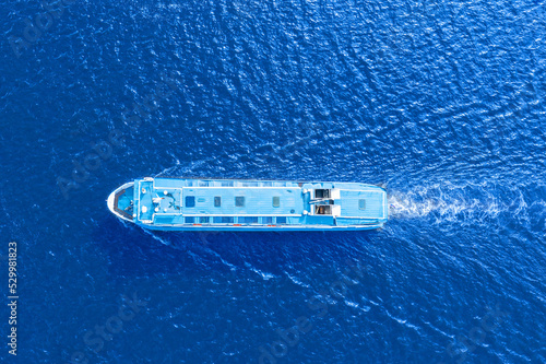 Small passenger ferry boat floats in sea waters, a view from a height exactly from above. © aapsky
